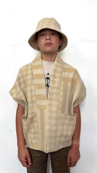 Person wearing a cream patterned jacket and matching hat against a white background turning to show all sides. 